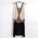 A 1920s evening dress decorated Art Deco geometric design in cream, gold and black beadwork,