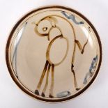 Manner of Svend Bayer, a stoneware plate painted a bird in blue and iron red, 19.