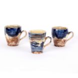 Nigel Lambert (born 1962), a set of three mugs, in blue, cream and coffee glazes, the tallest 10.