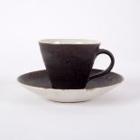 Lucie Rie (1902-1995), a teacup and saucer, in manganese glaze with cream interior, impressed mark,