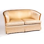 An Art Deco style sofa, with curved wood frame and cream upholstery,