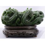 A Chinese spinach jade dragon bowl, the body carved with five dragons, together with a wooden stand,
