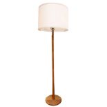 Modern teak floor lamp, having a single light, above a cylindrical standard and rising on a circular