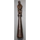 A Papua New Guinea pounder, having a figural finial to the top, with a widening cylindrical shank,