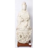 Chinese blanc de chine porcelain Guanyin, holding lotus sprigs, and seated on a lotus pedestal
