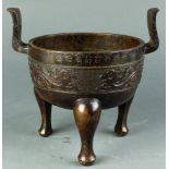 An incribed Chinese bronze censer, the deep bowl-shaped body cast with a band of confronting