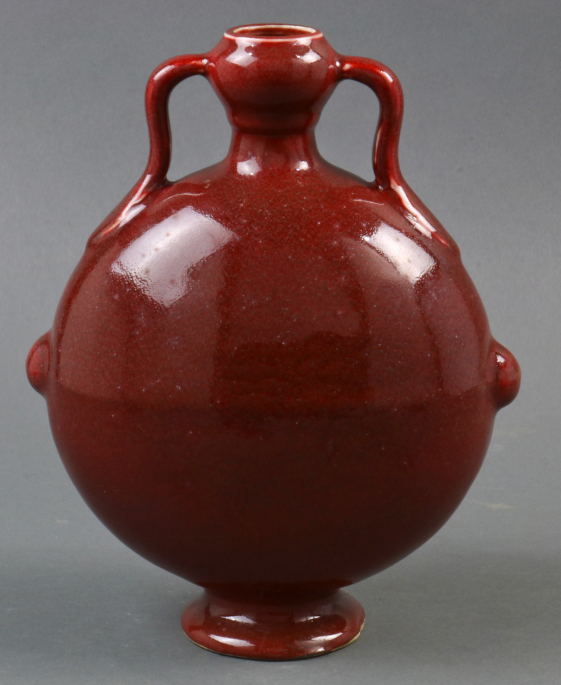 A Chinese copper red glazed porcelain moon-flask vase, of flattened circular shape raised on a low