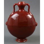 A Chinese copper red glazed porcelain moon-flask vase, of flattened circular shape raised on a low
