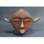 An African Eastern Pende mask, Democratic Republic of the Congo, of diamond shape with red, wide and