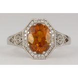 Sapphire, diamond and platinum ring Centering (1) oval-cut orange sapphire, weighing approximately