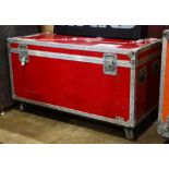 Red enameled road case having chrome hardware above a wheeled base