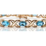 Blue topaz, 10k yellow gold bracelet Featuring (14) oval-cut blue topaz, weighing approximately 5.50