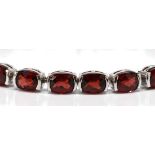 Garnet, 14k white gold bracelet Featuring (23) faceted top oval garnets, weighing a total of