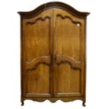 A Louis XV Provincial fruitwood armoire, the outset shaped bonnet top over twin paneled doors,