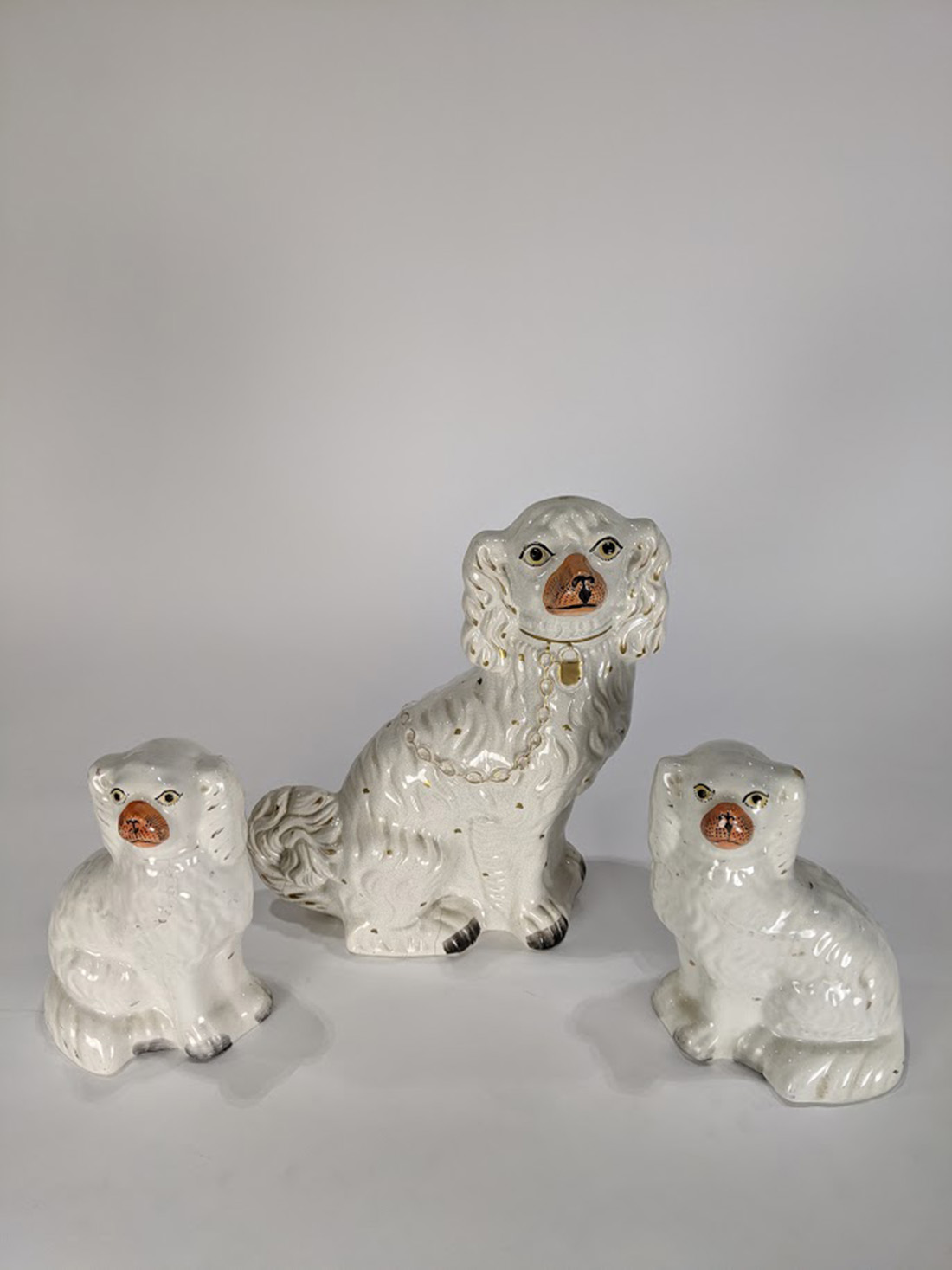 (lot of 3) Staffordshire spaniel figures, each executed in cream with gilt spots and painted