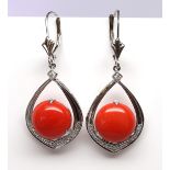 Pair of coral, diamond, 14k yellow gold earrings Featuring (2) round coral cabochons, measuring