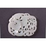 A Chinese white jade pendant, of a dragon figure surrounded by swirly patterns.