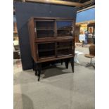 A Moderne oak tiered vitrine, having sliding doors opening to the adjustable shelves and rising on