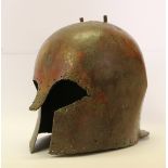 A Greek Corinthian form bronze helmet 7th century B.C, of domed form with a flaring neck guard and