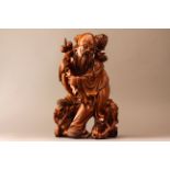 A Chinese wood figural carving of an old man with rock,