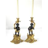 A pair of Rococo style gilt and patinated bronze candlesticks