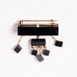 An onyx, jet and eighteen karat gold brooch