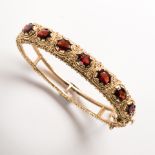 A Victorian Revival garnet and fourteen karat gold bangle bracelet