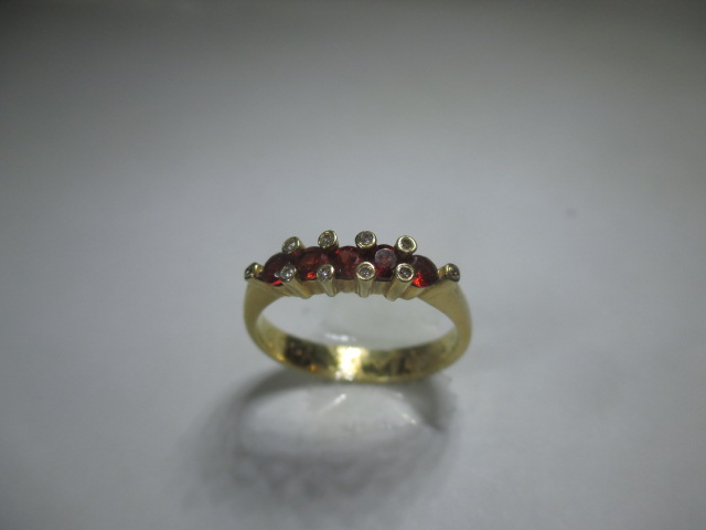 An 18ct yellow gold ring set with a central row of rubies flanked by 10 small diamonds.