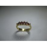 An 18ct yellow gold ring set with a central row of rubies flanked by 10 small diamonds.