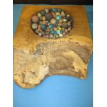 A large quantity of antique clay marbles in a rustic wood display bowl