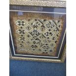 An antique hand woven rug in modern glazed frame