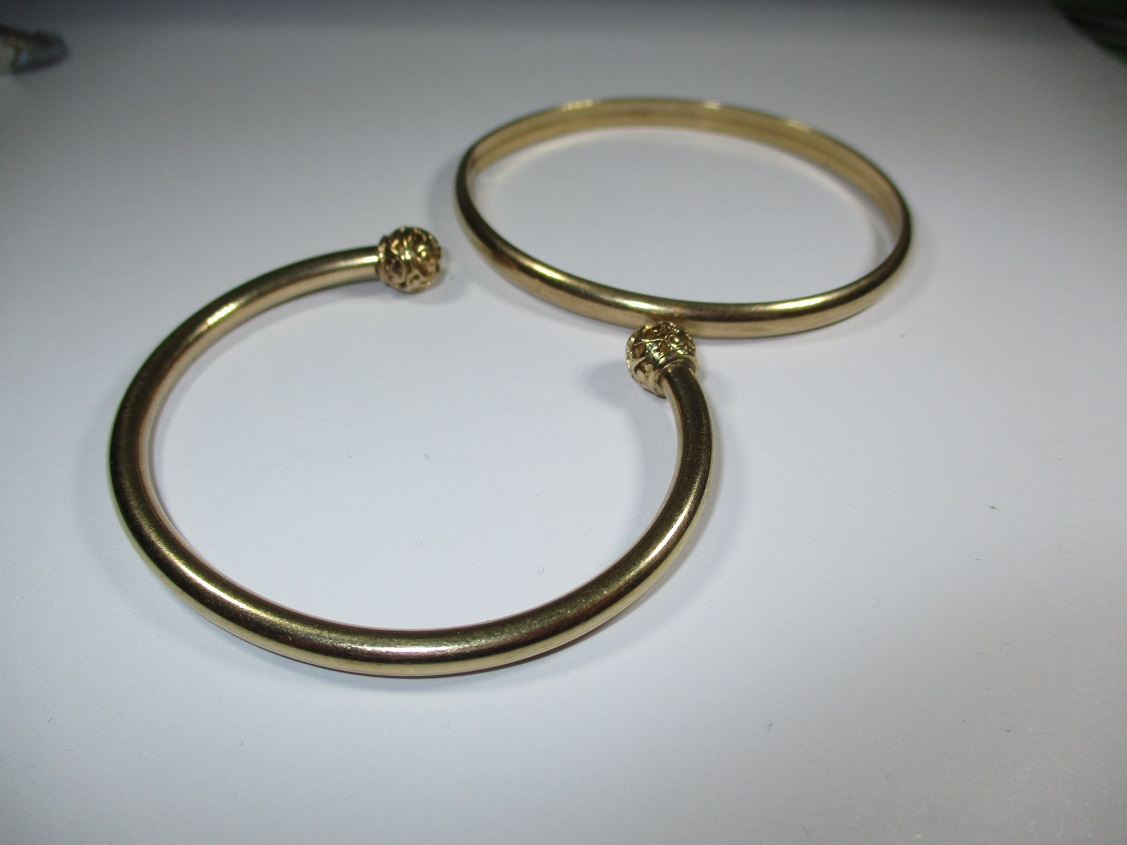 A gold torque type bangle and another yellow metal example