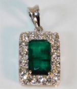 An 18ct white gold emerald pendant framed by appro