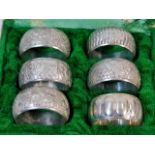 A case of six decorative white metal napkin rings