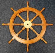 A wooden reproduction yacht wheel with brass centr