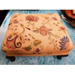 A small footstool with embroidered cover