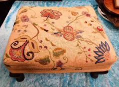 A small footstool with embroidered cover