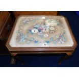 A low level glass topped table with tapestry decor