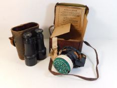 A pair of binoculars twinned with a boxed gas mask