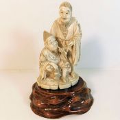 An ivory figure with naturalistic carved wood base