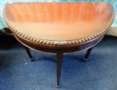 An antique mahogany card table with pie crust edge