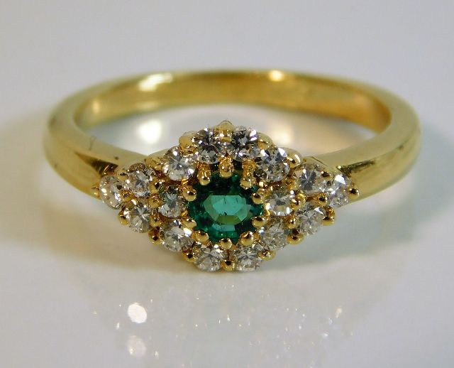 An 18ct gold diamond & emerald ring set with appro