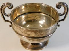 A plain silver bowl with two handles, some faults