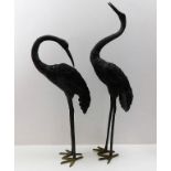 A pair of decorative metal garden herons, tallest