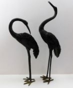 A pair of decorative metal garden herons, tallest