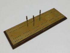 A brass cribbage board 12.75in long x 4.25in wide