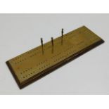 A brass cribbage board 12.75in long x 4.25in wide