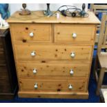 A pine chest of five drawers with ceramic fittings