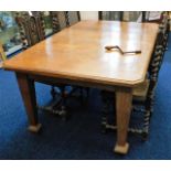 An antique extendable oak table with winder