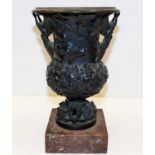 A 19thC. bronze cup with figurative handles on a s